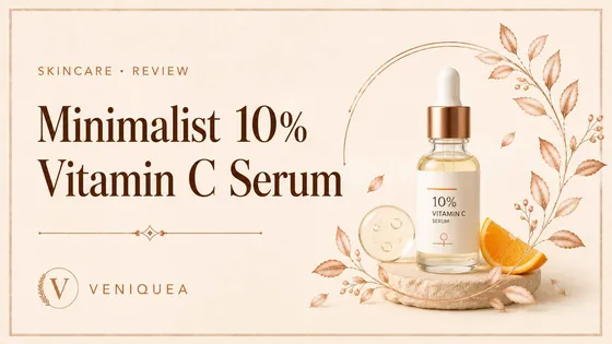 A vitamin C serum dropper bottle beside a single drop on an ivory surface